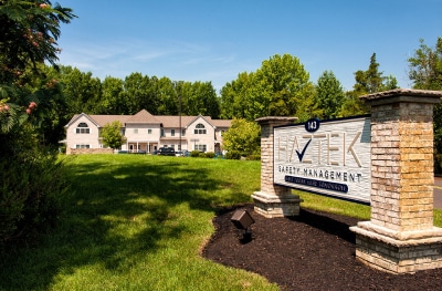 HazTek Inc. safety management headquarters situated in a picturesque landscape featuring large trees and a blue sky.