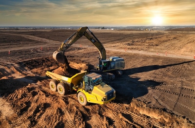 Safety consulting company at work site showing backhoe operation at sunrise in a large, open field.