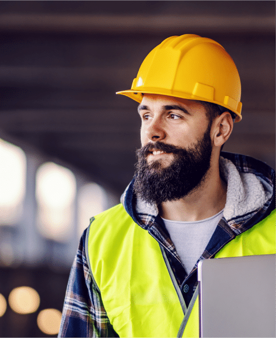 HazTek Inc. professional leading safely while holding a laptop at construction site.