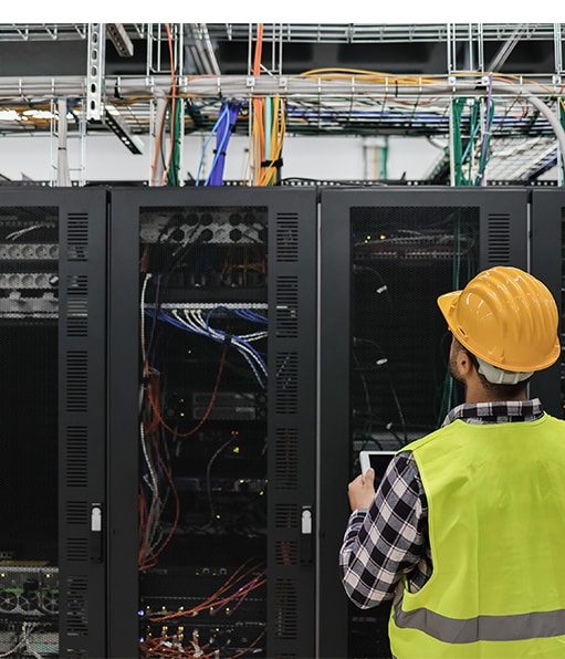 Haztek Inc. - A site safety expert wearing a hard hat and vest, analyzing wiring to ensure exemplary data center health and safety.