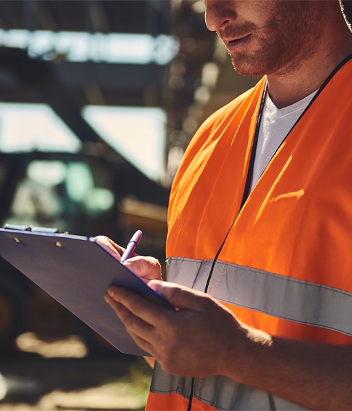 Haztek Inc. - A focused site safety professional recording data using a pen and clipboard.