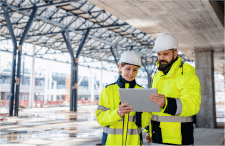 Two managers leading safely while reviewing plans at construction site.