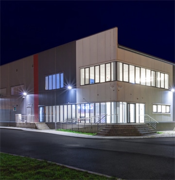 Nighttime view of large building with internal and external lights on.