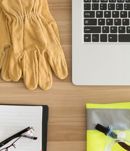 Tabletop display of items used by safety consulting companies, including gloves, glasses, and laptop.