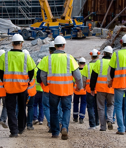 Rows of construction workers walking while wearing protective equipment during OSHA safety training program.