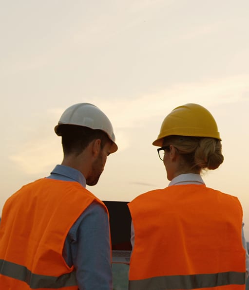 Two renewable energy safety professionals working on a laptop outdoors.